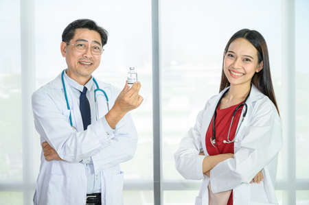 Couple of Asian adult  male doctor and Asian young female doctor wearing formal white coat teamwork brainstorm meeting at the hospital. Healthcare specialist people.の写真素材