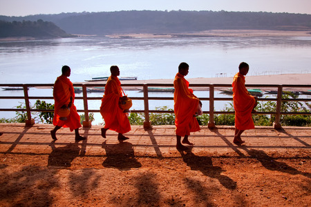 Buddhist monks walk with a bowl of the Mekong Riverのeditorial素材