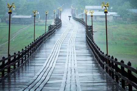 Unidentified Students umbrella walks in the rain on the bridge to school at 2062013  time 6:28 o'clock. in Kanchanaburi Thailand.の写真素材