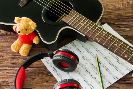 Acoustic guitar, headphones and sheet musical noteson the table.の写真素材