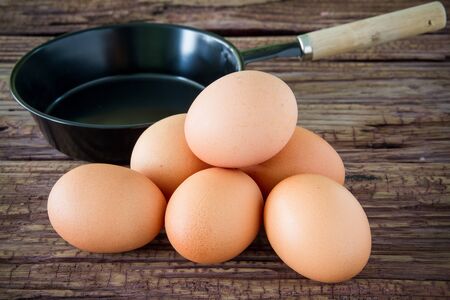 Brown chicken egg and iron pan on the tableの写真素材