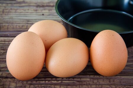Brown chicken egg and iron pan on the tableの写真素材