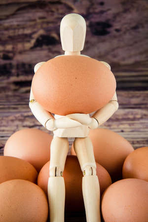 wooden puppet hold the brown chicken eggの写真素材