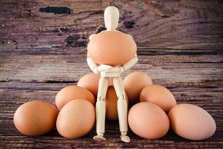 wooden puppet hold the brown chicken eggの写真素材
