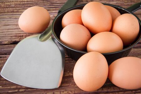 Brown chicken egg and iron pan on the tableの写真素材