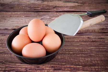 Brown chicken egg and iron pan on the tableの写真素材
