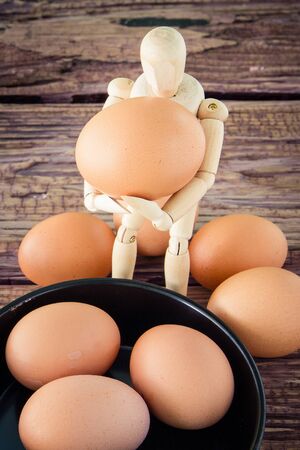 wooden puppet hold the brown chicken eggの写真素材
