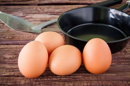 Brown chicken egg and iron pan on the tableの写真素材