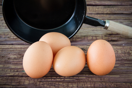 Brown chicken egg and iron pan on the tableの写真素材