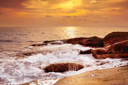 Seaside with stone and colorful sky at sunsetの写真素材