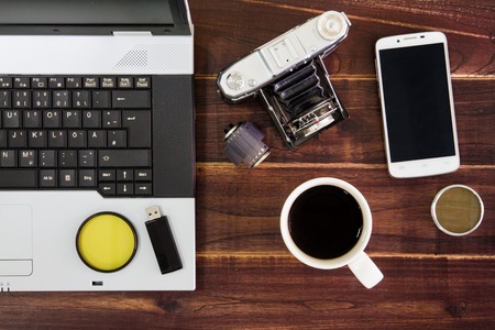 Notebook computer on the desk.USB flash drive stick,coffee cup,camera,smartphoneの写真素材