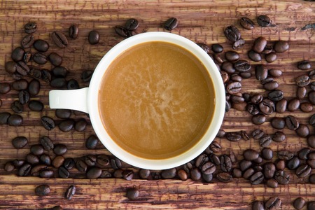White coffee cup with roasted coffee beans on old wood.の写真素材