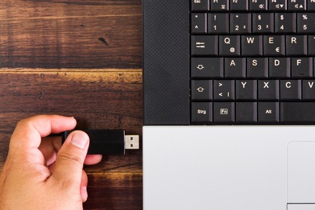 Laptop computer and hand with USB flash drive. selective focusの写真素材