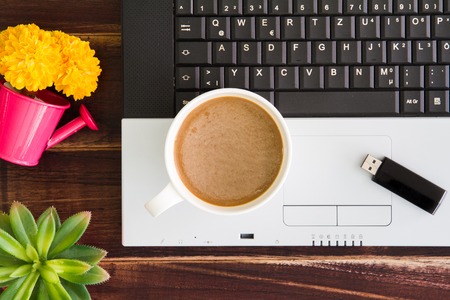 Notebook computer with coffee cup, computer and flower. View from above with copy spaceの写真素材