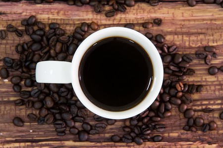 White coffee cup with roasted coffee beans on old wood.の写真素材
