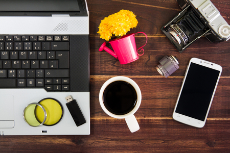 Notebook computer on the desk.USB flash drive stick,coffee cup,camera,smartphoneの写真素材
