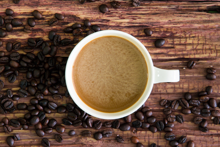 White coffee cup with roasted coffee beans on old wood.の写真素材