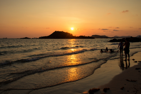 Happy children and family playing on the beach at the sunset time.の写真素材