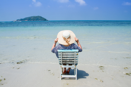 Woman sitting on a beach chair enjoying a summer day at the beach. Concept on the beachの写真素材