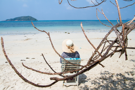 Woman sitting on a beach chair enjoying a summer day at the beach. Concept on the beachの写真素材