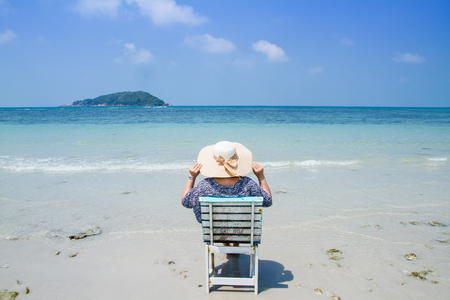Woman sitting on a beach chair enjoying a summer day at the beach. Concept on the beachの写真素材