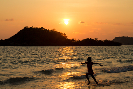 Happy children playing on the beach at the sunset time.の写真素材