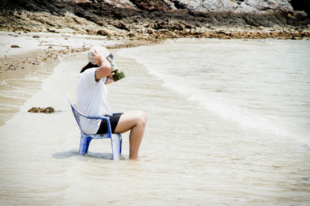 Girl with gas masks sitting on a chair at the sea.の写真素材