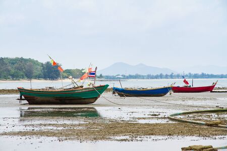 An old fishing boat moored beached on the beach at low tideの写真素材