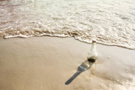 Empty glass bottle on the beach, garbage on beach, concept of beach environmentの写真素材