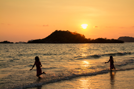 Happy children playing on the beach at the sunset time.の写真素材
