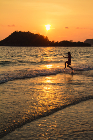 Happy children playing on the beach at the sunset time.の写真素材