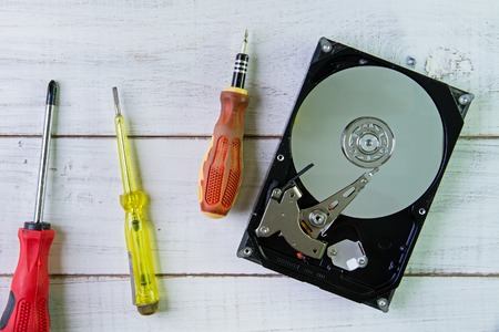 Screwdrivers and a hard disk  on the white wooden background.の写真素材