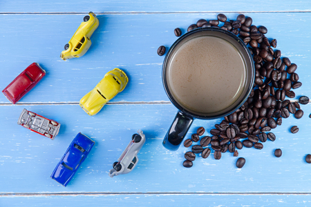 Coffee cup with coffee beans and toys car on the blue wooden background.の写真素材