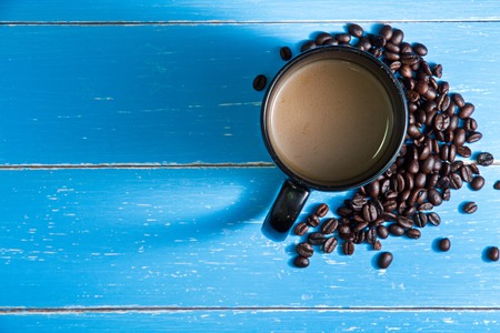 Coffee cup with coffee beans on the blue wooden background.の写真素材