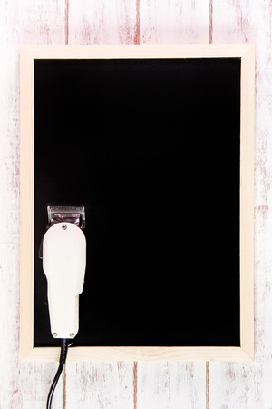 Blank blackboard and Clipper Barber on wooden table.Template mock up for adding your design and leave space beside frame for adding more text.の写真素材