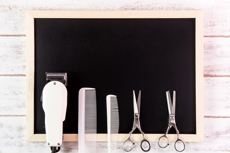 Blank blackboard, Scissors hairdresser and Clipper Barber on wooden table.Template mock up for adding your design and leave space beside frame for adding more text.の写真素材