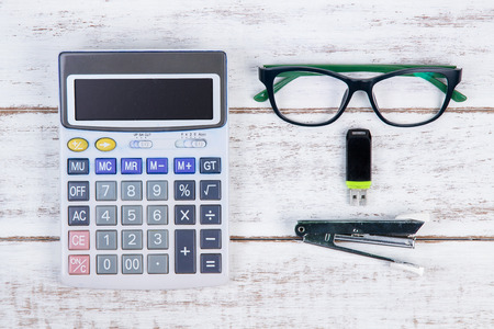 Top view of calculator and glasses on the accountant white table.Business concept.