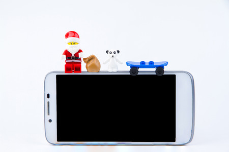Nonthaburi, Thailand - November, 26, 2016 : Lego Santa Claus sitting on the edge of smartphone and giving gifts at Christmas.Theme Christmas day background.のeditorial素材