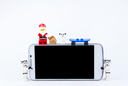 Nonthaburi, Thailand - November, 26, 2016 : Lego Santa Claus sitting on the edge of smartphone and giving gifts at Christmas.Theme Christmas day background.のeditorial素材