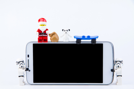 Nonthaburi, Thailand - November, 26, 2016 : Lego Santa Claus sitting on the edge of smartphone and giving gifts at Christmas.Theme Christmas day background.のeditorial素材