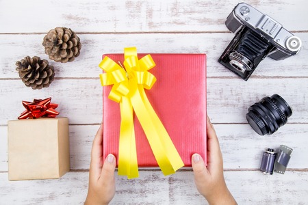 Hand and present gift box design wrapped in color paper with bows on a white wooden background.View...