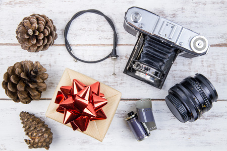 Present gift box design wrapped in color paper with bows and vintage old camera on a white wooden background.View from above with copy space.Christmas and New Year background,の写真素材