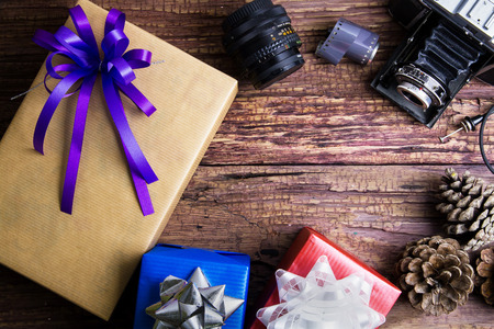 Present gift box design wrapped in color paper with bows and vintage old camera on a wooden background.View from above with copy space.Christmas and New Year background,の写真素材