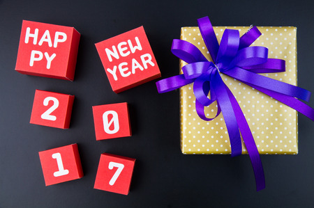 Present gift box and Happy new year 2017 number on red paper box cubes on black background with copy...