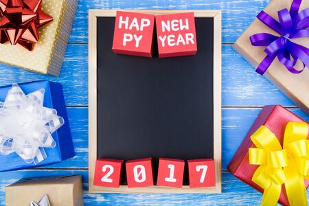Present gift box, Blackboard and Happy new year 2017 number on red paper box cubes on blue wooden background with copy space.Year of the Cock.2017 New Year concept background.の写真素材