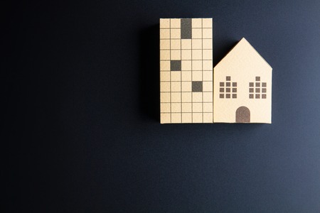 Home architectural model paper box cubes on black background with copy space.Real estate concept.
