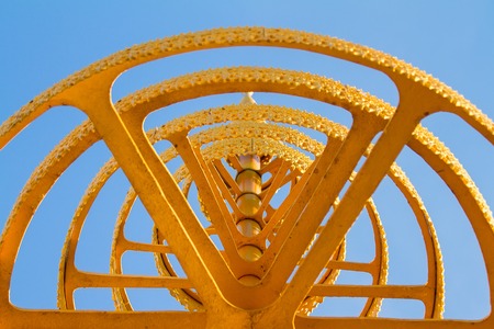 A gold tiered umbrella under blue sky background.の写真素材
