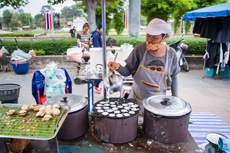 Uthai Thani, Thailand - December, 17, 2016 : Unidentified Woman selling "Kanom Krok"  kind of Thai sweetmeat Coconut milk mix with powder fried dessert on street market in the morning at Uthai Thani, Thailandのeditorial素材