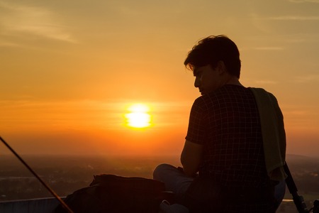 Uthai Thani, Thailand - December, 17, 2016 : Unidentified Silhouette of photographer taking pictures with camera in sunset sky at Wat Sangkat Rattana Khiri on Khao Sakae Krang mountain in Uthai Thani, Thailandのeditorial素材