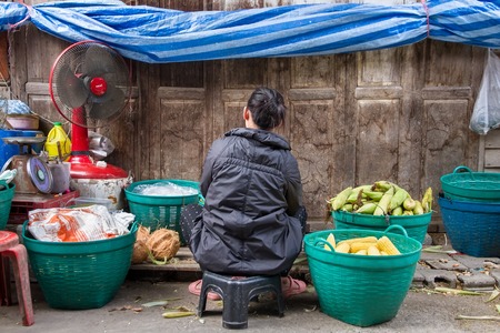 Uthai Thani, Thailand - December, 17, 2016 : Unidentified Woman sitting stripping corn on street market in the morning at Uthai Thani.Uthai Thani is small town in central Thailandのeditorial素材